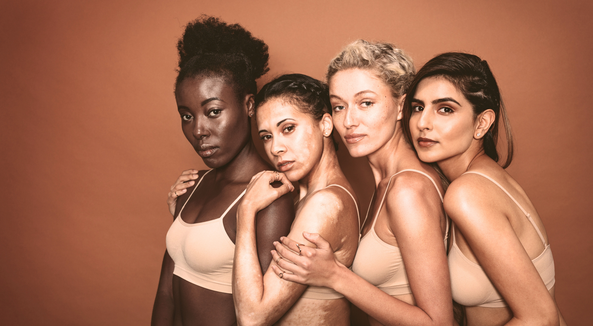Four diverse women, terracotta background